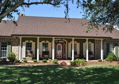 Beautiful home with white pillars, red front door and metal roof