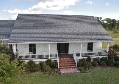 White home with brown metal roof and brick stairway