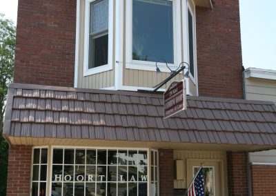 Brick commercial building with a brown metal roof and an American Flag hanging by the front entrance