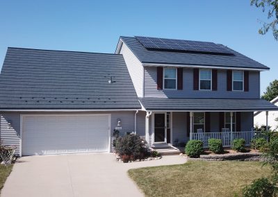 Two-story suburban home with gray metal roof and rooftop solar panels