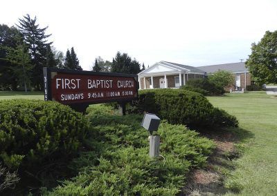 Exterior view of First Baptist Church at 3185, with a dark red marquee sign listing Sunday services